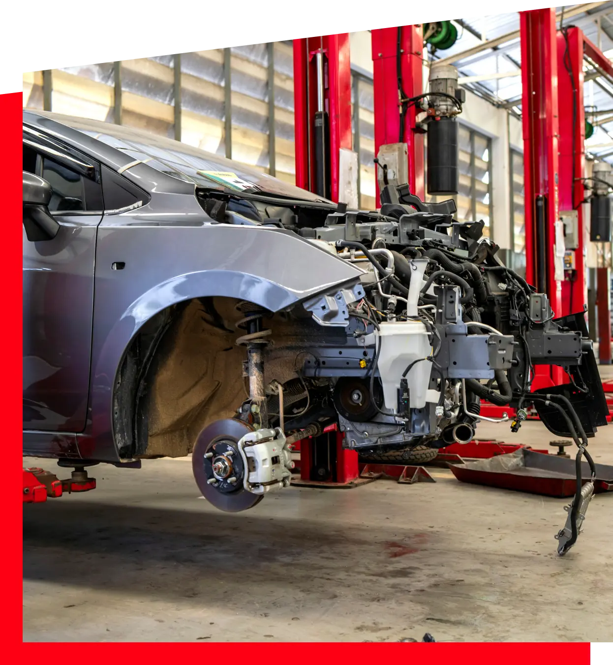 A car is lifted on a hydraulic jack in a garage, with tools scattered around for maintenance work.