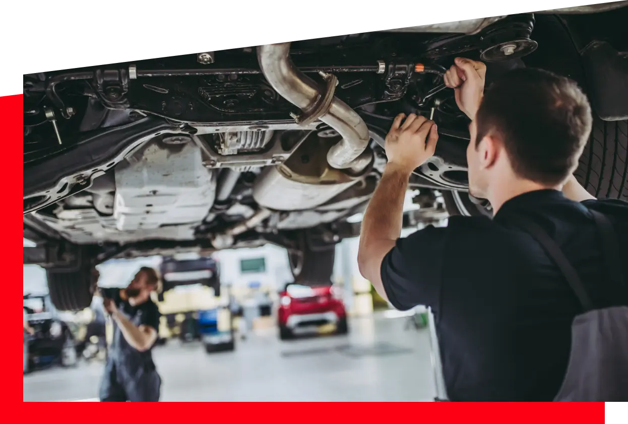 Two mechanics collaborating on a car repair inside a well-equipped garage, focused on their task.