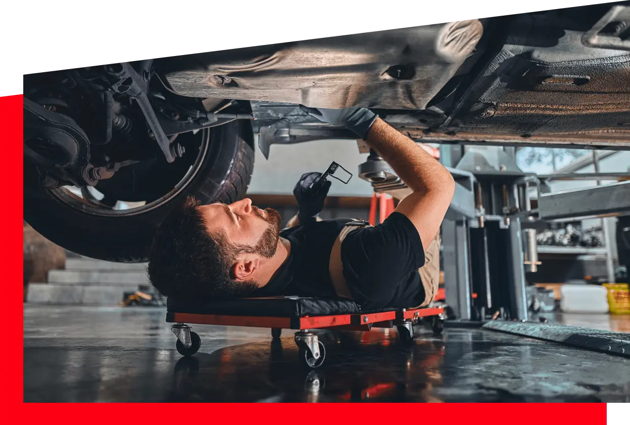 A man engaged in automotive repair, examining the vehicle's undercarriage